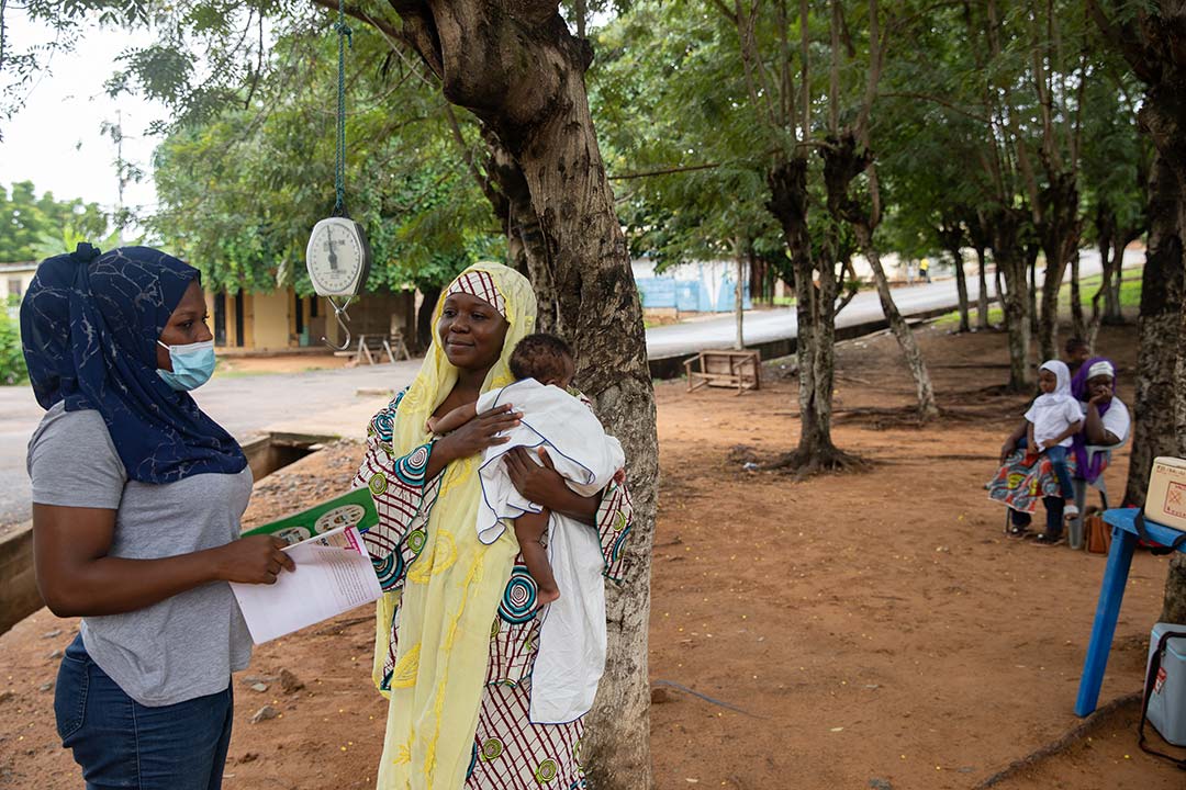 Un agent de santé interagit avec une mère lors d'un contrôle médical et d'une vaccination communautaires. Gavi/2022/Nipah Dennis