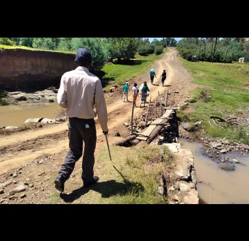 A group of people crossing what used to be a bridge connecting the Ha Ramapepe people with their counterparts over the river. Credit: Monyane Khau