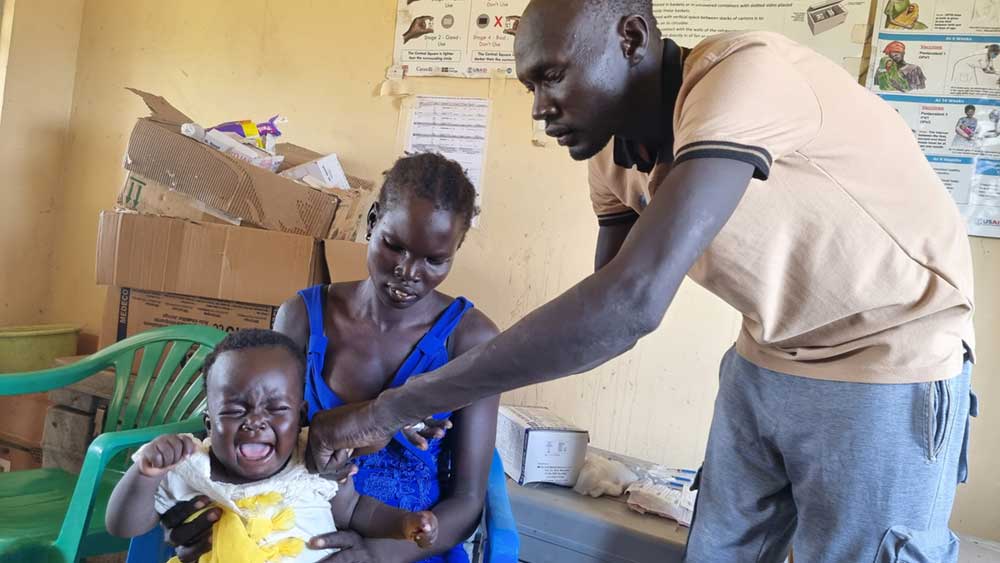 Vaccinator Ahoch-Thon immunizing a child. Credit: Winnie Cirino