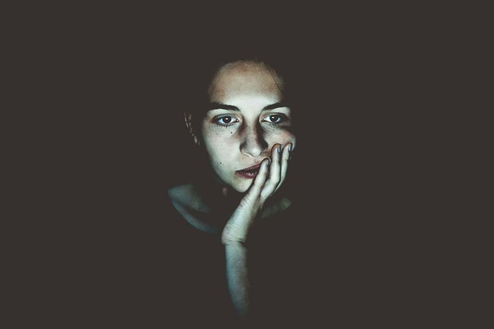 Woman sitting in a dark room.