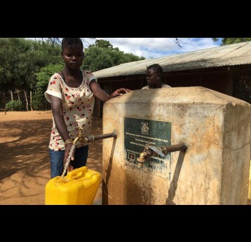 Locals getting water from a solar pump system in Nabilatuk district. Water flows automatically from several taps, meaning users don’t have to queue for long hours. Credit: Pius Sawa