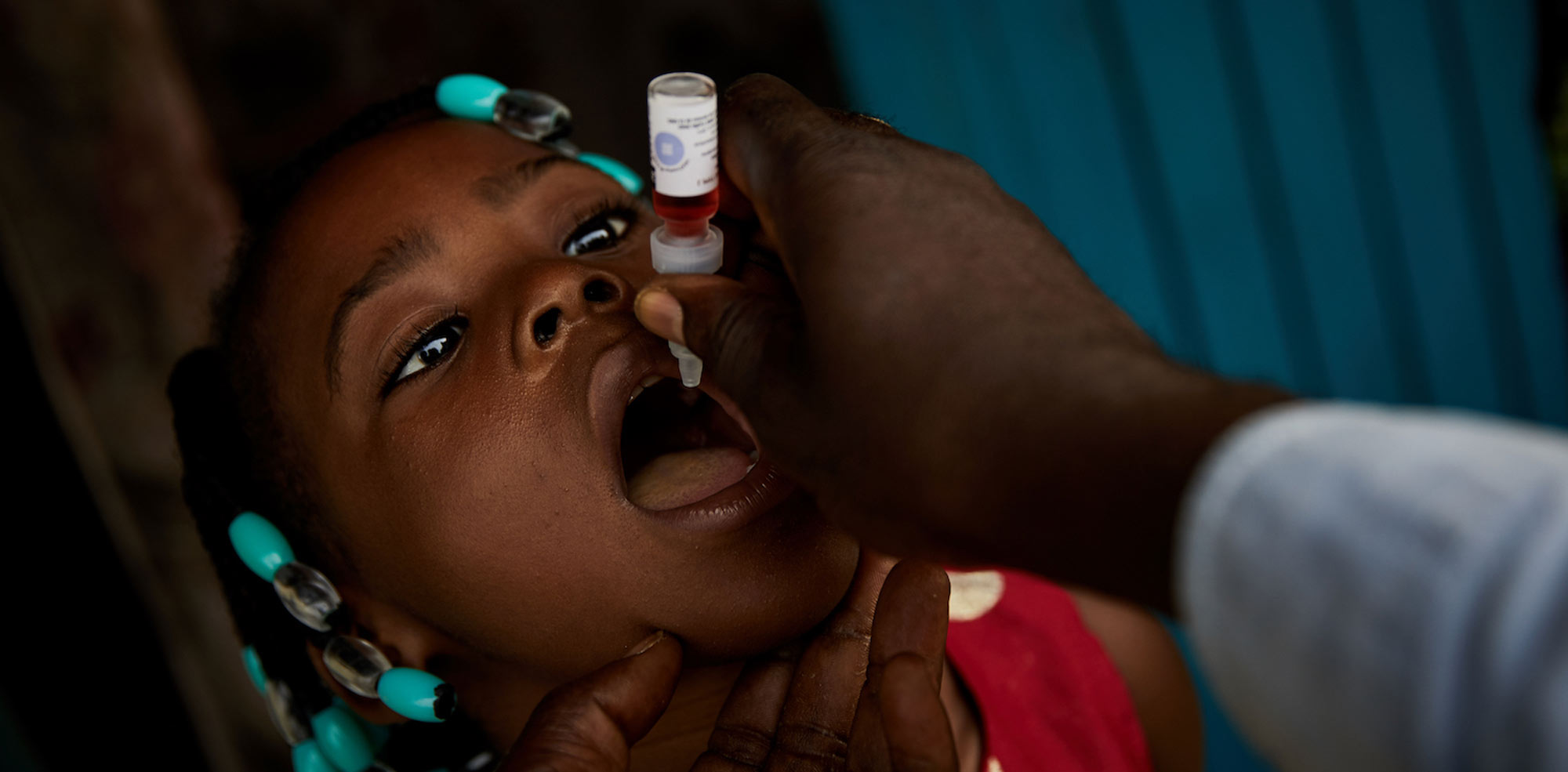 A health worker administers two drops of polio vaccine to four-year old Daniella Ntiese in Bandundu. “It’s important that no child is left out,” he says © Hugh Cunningham