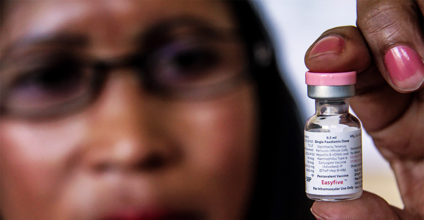 Woman holding up a vaccine vial