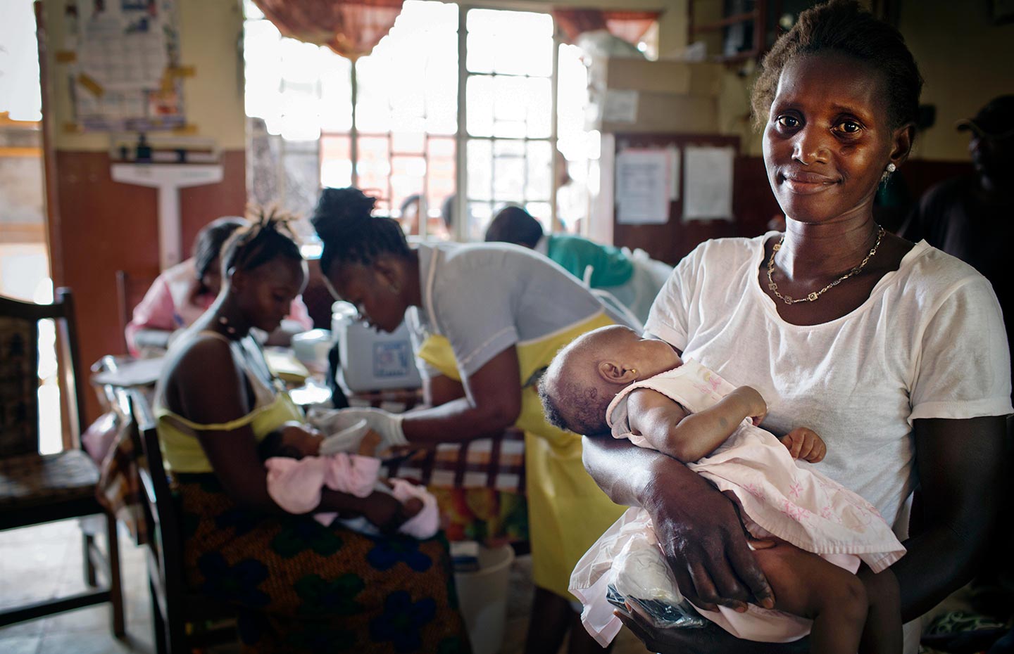 A woman waits with her daughter to be vaccinated at a maternal and child health clinic in a health centre in Freetown, Sierra, Leone on 17 February 2016. Gavi/2016/Kate Holt/Sierra Leone