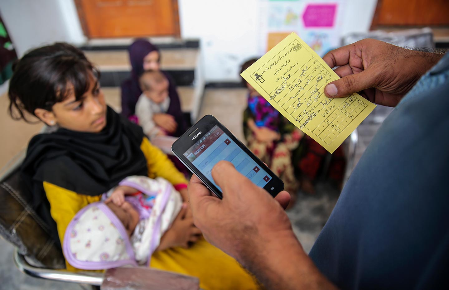 GAVI/2017/Asad Zaidi-An EPI worker, Mohammad Saim, entering Adeel’s (15 days old) data into the EVACC mobile app during an urban slum field visit in Bund Road Lahore, Punjab province