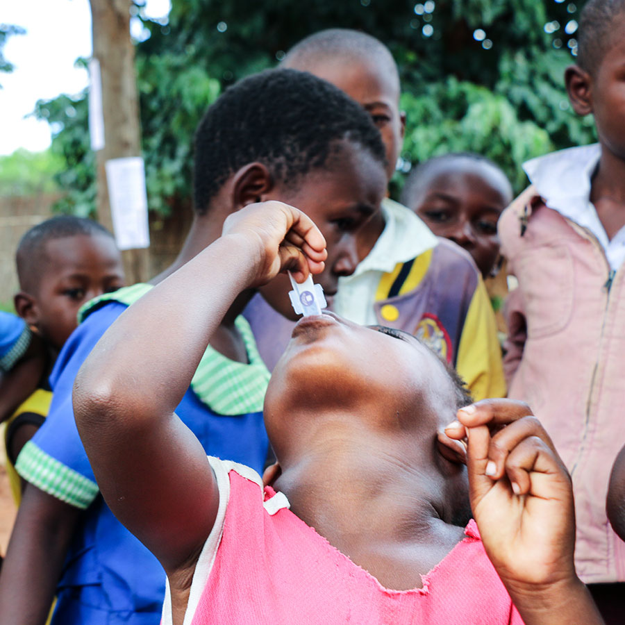 Little girl administering oral cholera vaccine to herself in Malawi