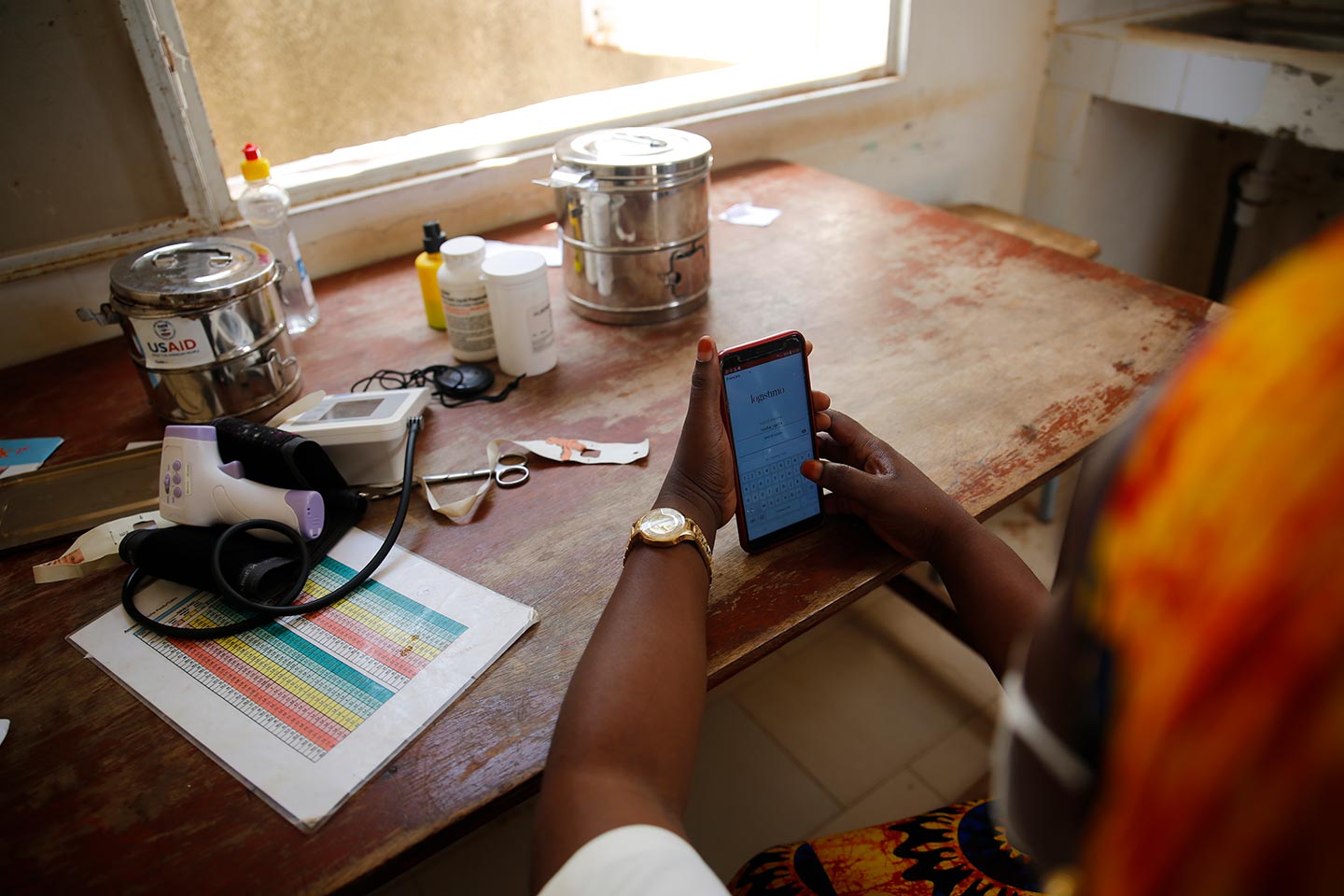 A health worker sits at a desk using a mobile phone. Credit: Gavi/2020/Maya Hautefeuille