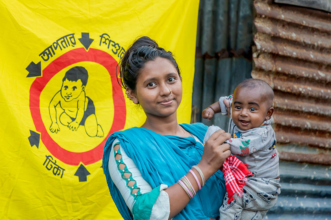 On 11 November 2023 in Bangladesh, a mother holds her child during a HPV vaccination campaign in Bede Bohor village of the Aftab Nagar neighbourhood of the Bonosree residential area of Dhaka. This minority community has a high prevalence of preventable diseases. © UNICEF/UNI493457/Satu