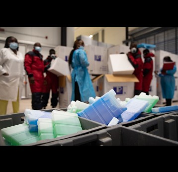 Le personnel de la chaîne du froid déballe les vaccins COVID-19 pour le stockage dans la chambre froide. Entrepôt de stockage de vaccins, commune de Kinkole, Kinshasa, RDC. – Crédit: Desjardins Sibylle