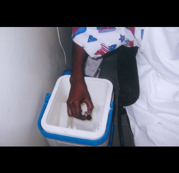 A health worker in Senegal pulls a vaccine vial out of a cold storage vaccine carrier. Ensuring that vaccines are kept at the right temperature is just one way that countries are preparing to immunize their populations against COVID-19. Photo: PATH.