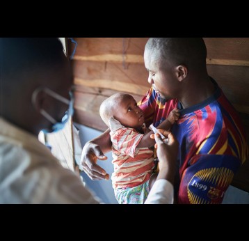 A father holding his son while he finally gets vaccinated – Gavi/2021/Christophe Da Silva