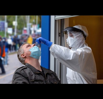 Medical worker in protective gear collects a sample from man during pandemic of COVID-19.