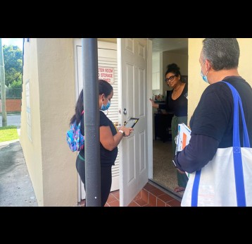 In their canvassing of a predominantly Cuban American neighborhood in October, Alejandro Díaz (right) and another community outreach worker, María Elena González (left), spoke with Gloria Carvajal about how to get a covid-19 test. (Verónica Zaragovia/WLRN)
