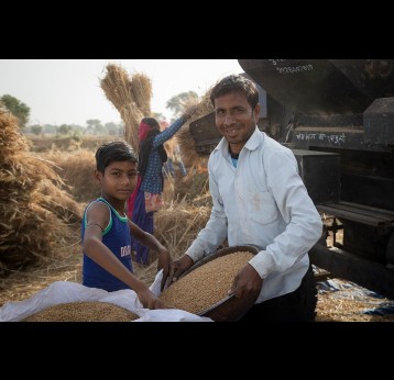 A boy and his Father filling a bag with grain. Rajasthan, India. Credit: Gavi/2021/Benedikt v.Loebell