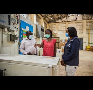 Dr. Rose Jalang’o, Team Lead Malaria Vaccine Implementation Program in Kenya and Dr. Josephine Njoroge, Technical Officer Malaria Vaccine Implementation Program (WHO) interact with a depot manager at the Kisumu Regional Vaccine Depot. Gavi/2021/White Rhino Films-Lameck Orina