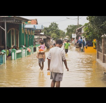 People walking in a flooded street as a result of climate change. Photo by Misbahul Aulia on Unsplash