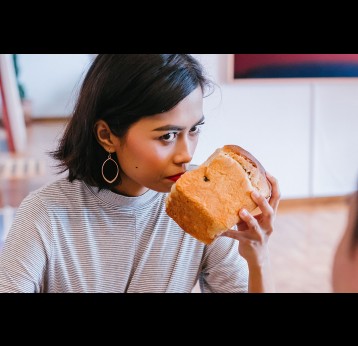 A woman trying to smell bread. Photo by mentatdgt from Pexels
