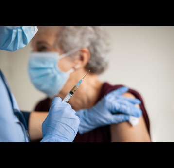 Close up of general practitioner about to vaccinate a senior woman.