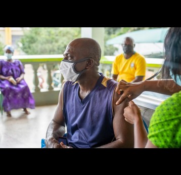 An old African man receiving a vaccine injection from a healthcare provider