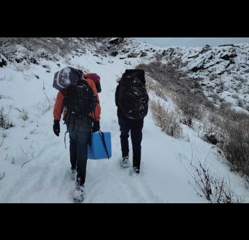 Health workers of Namkha Health Post in Humla district walking on the snowy road with vaccine carrier. Credit : Lundup Dorje Lama