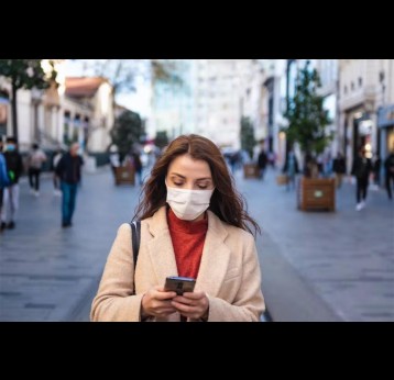 Woman walking on a street wearing a face mask. Credit: epic_images/Shutterstock