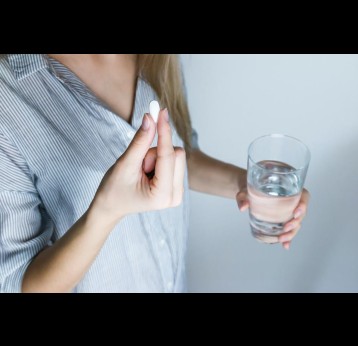 Woman holding a pill and a glass of water. Credit: JESHOOTS.com via Pexels