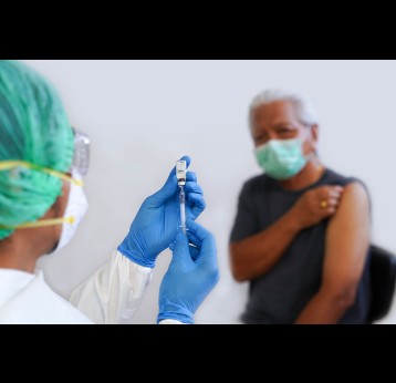 Doctor in full protective equipment, preparing a vaccine.