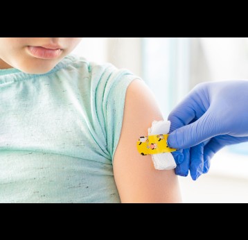 Doctor applying kids funny adhesive plaster after COVID-19 vaccination.