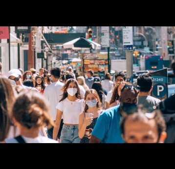 Masked people on a busy street. Credit: Yoav Aziz on Unsplash
