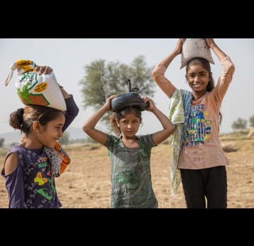 Three girls, carrying bags of grain on their head, Rajasthan, India. Credit: Gavi/2021/Benedikt v.Loebell