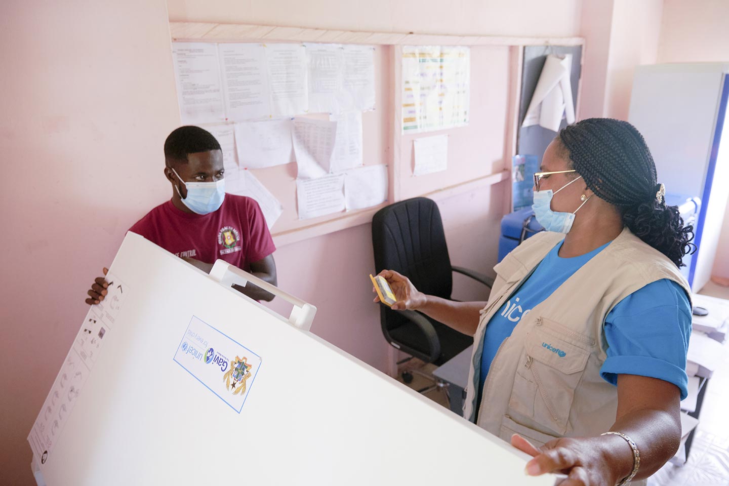 Charity Nikoi, responsable de la communication pour le développement à l'UNICEF, vérifie les équipements de la chaîne du froid et le stockage des vaccins au centre de santé de Pepease dans le district de Kwahu East de la région orientale le 8 octobre 2020.  ©UNICEF/ANNANKRA