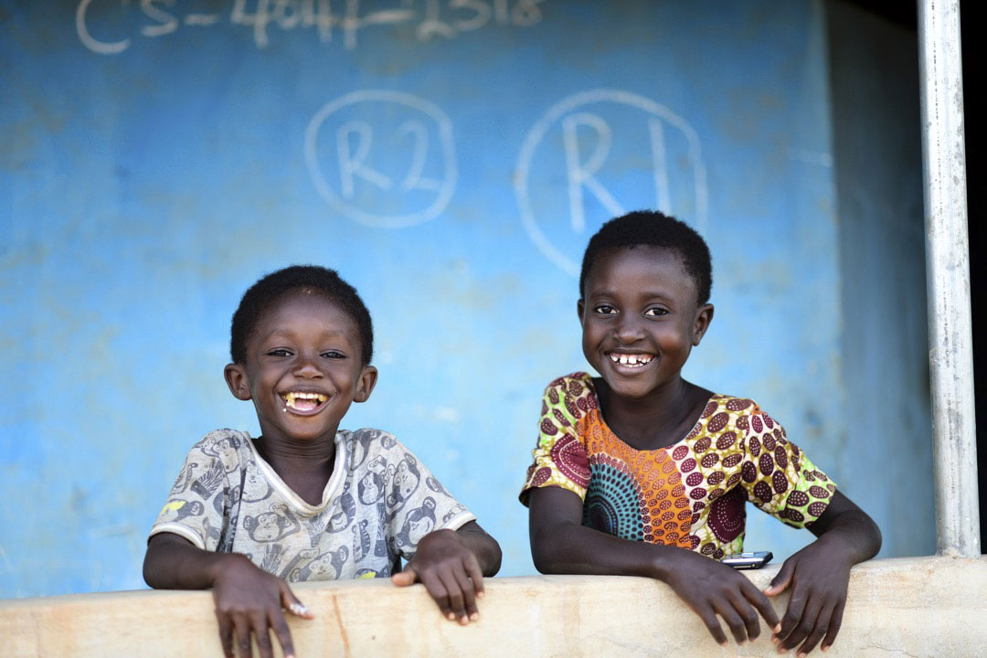Chez eux, deux enfants sourient à la caméra après avoir été vaccinés contre le poliovirus. Derrière eux, leur maison a été marquée pour montrer qu'elle a été visitée lors des premiers et deuxièmes tours de la campagne, le 12 octobre 2020. ©UNICEF/BUTA