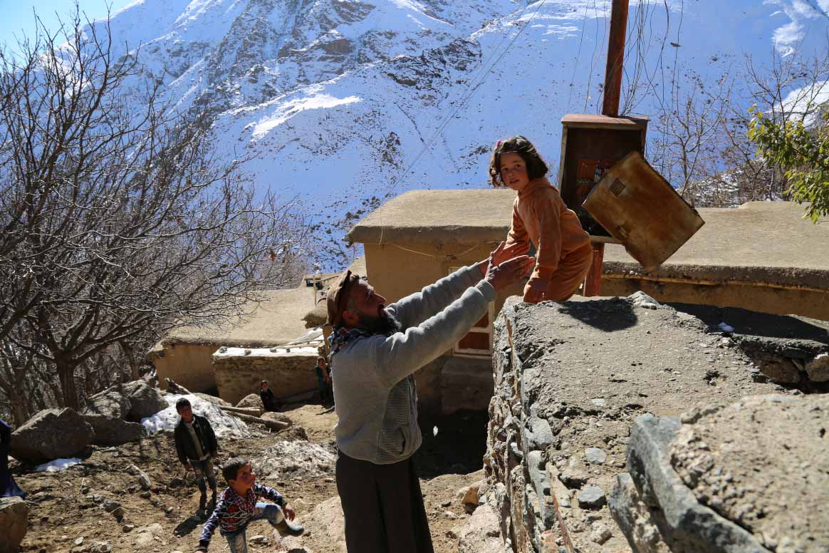 Arsalan Khan helps Khadija, four years old, to climb down a wall in Doshakh village, Rukha district of Panjshir province. ©Ahmadullah Amarkhil/WHO Afghanistan