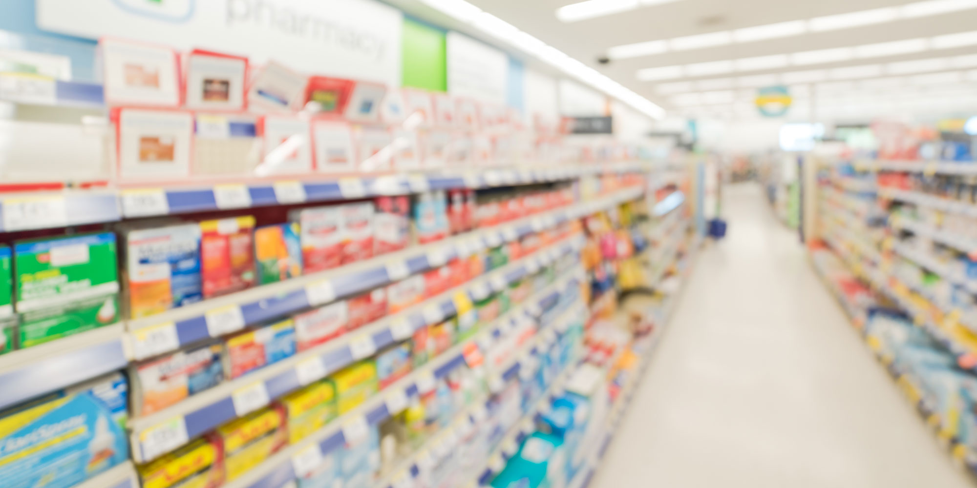 Blurred abstract background inside pharmacy store with arranged variation of pharmaceutical and medical supplies product in label on shelves display.