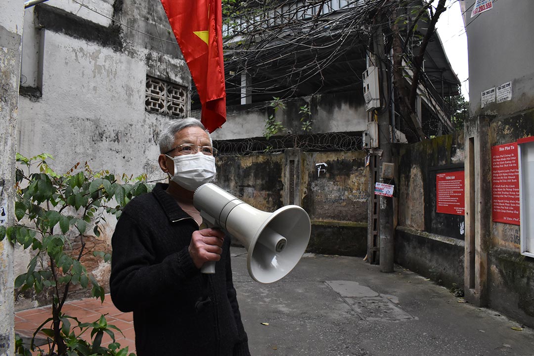 Mr Han Cong Khanh holds a loudspeaker in an alley of his neighbourhood in Hanoi, Vietnam