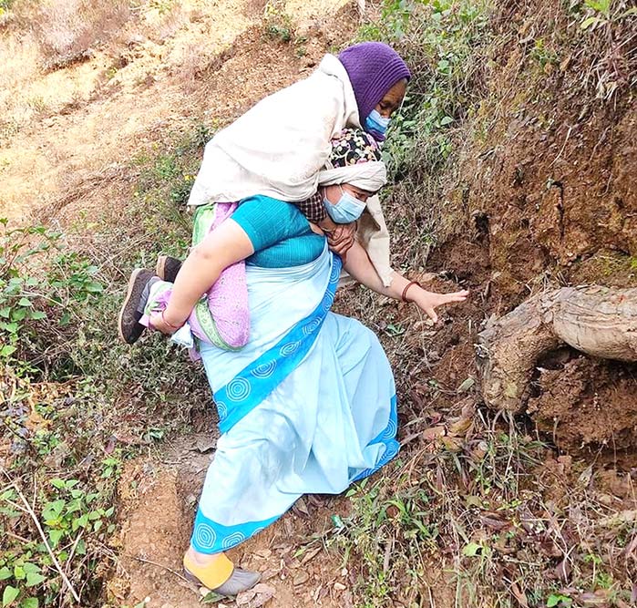 Lila Thapa, a female community health worker from Gulmi district in western Nepal carrying an old woman to her COVID-19 vaccination.