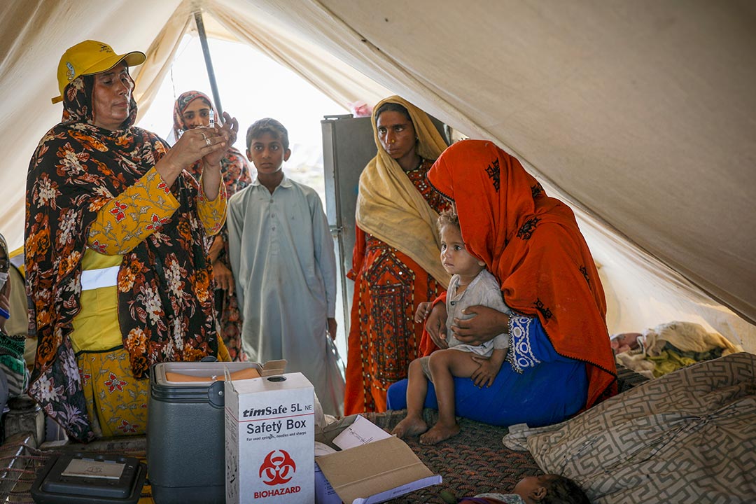 Hakim Zadi (left), a trained midwife prepares a TCV shot for Tahseen, aged two. In Sohbatpur city, as in other parts of Pakistan, many displaced families are sheltering in tents after the summer’s floods inundated their homes. Credit Gavi/Asad Zaidi