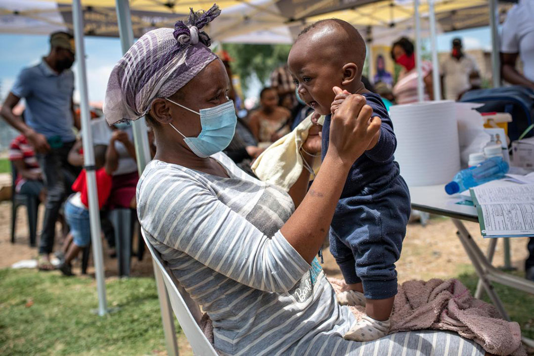 Mother Neliswa Mnana holds her son, 6-month-old Phatu, at a pop-up vaccination site run by the Zwakala campaign in South Africa. @ UNICEF/UN0595761/Paul