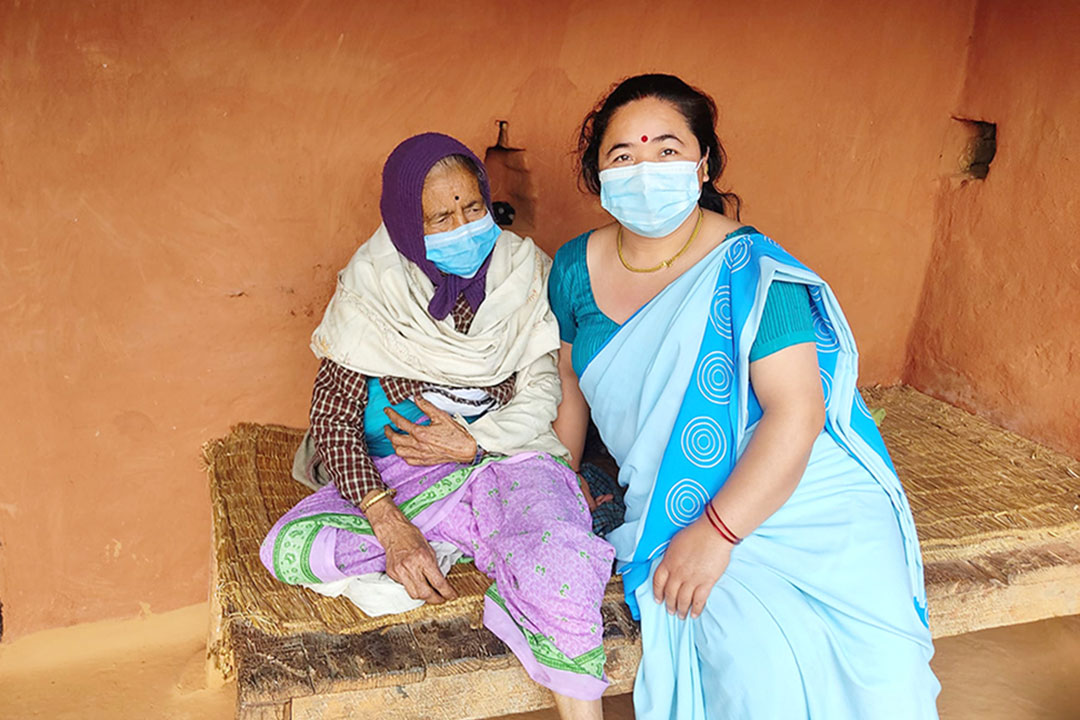 Lila Thapa (right), a female community health worker, with Devi Kali Tandan after she was taken to her home from Gaudakot health post.
