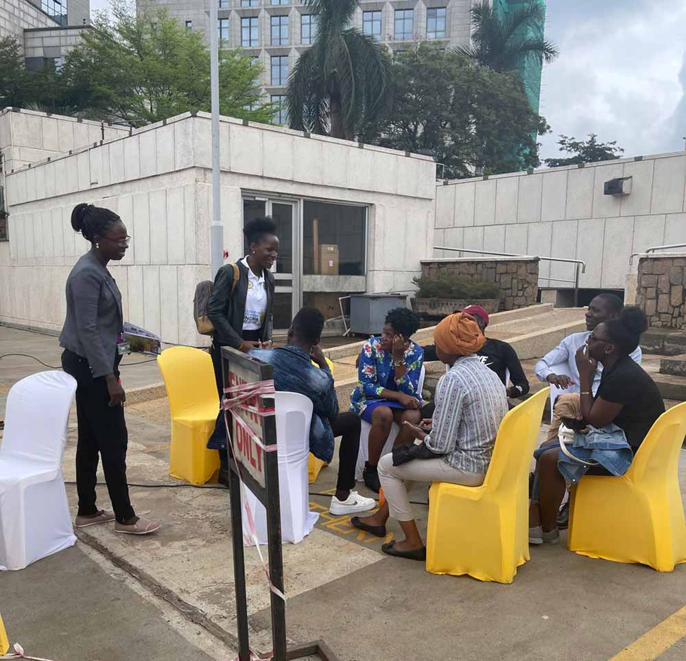 Doreen Naiga (standing right) talking to young people about COVID-19 vaccination near Uganda's Parliament. The young advocate uses every opportunity to encourage youths in the country to vaccinate against the coronavirus. Credit: Doreen Naiga