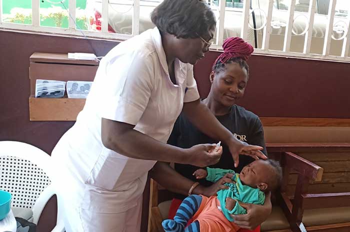 Isabella Bayena watches on as a nurse at the Etoug-Ebe Baptist Hospital administers oral polio vaccine to her son.