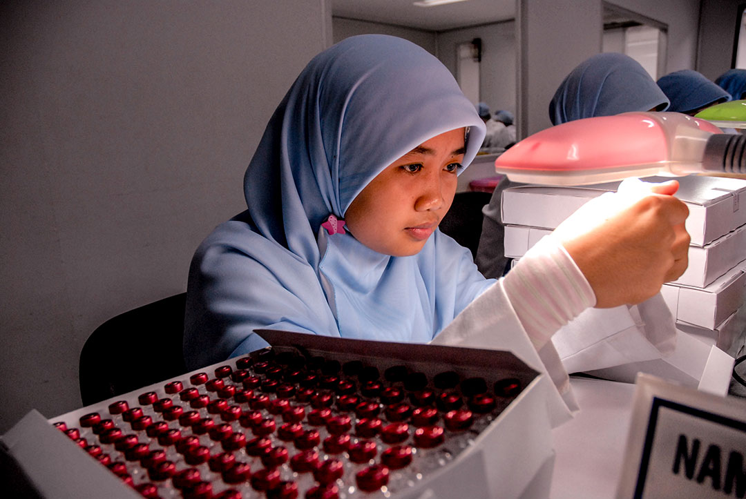 Workers look at the filling process of HepB vaccine filled in Uniject syringes at the a serum factory. Credit: GAVI/2007/Edy Purnomo