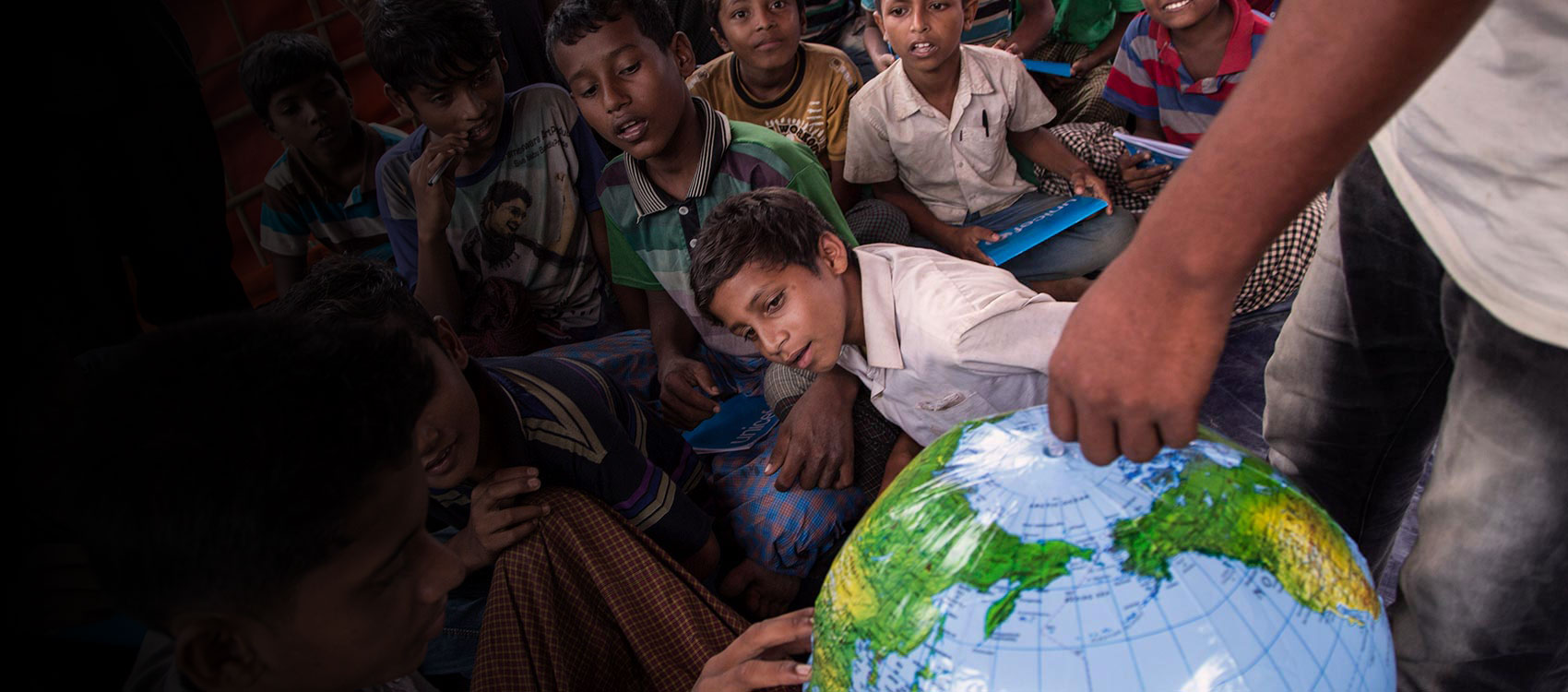 © UNICEF/UN0141027/LeMoyne/Bangladesh- Students look at an inflatable globe, part of the educational supplies contained in a School-in-a-Box, at a new Transitional Learning Centre in the Uchiprang refugee camp, near Cox's Bazar, Bangladesh