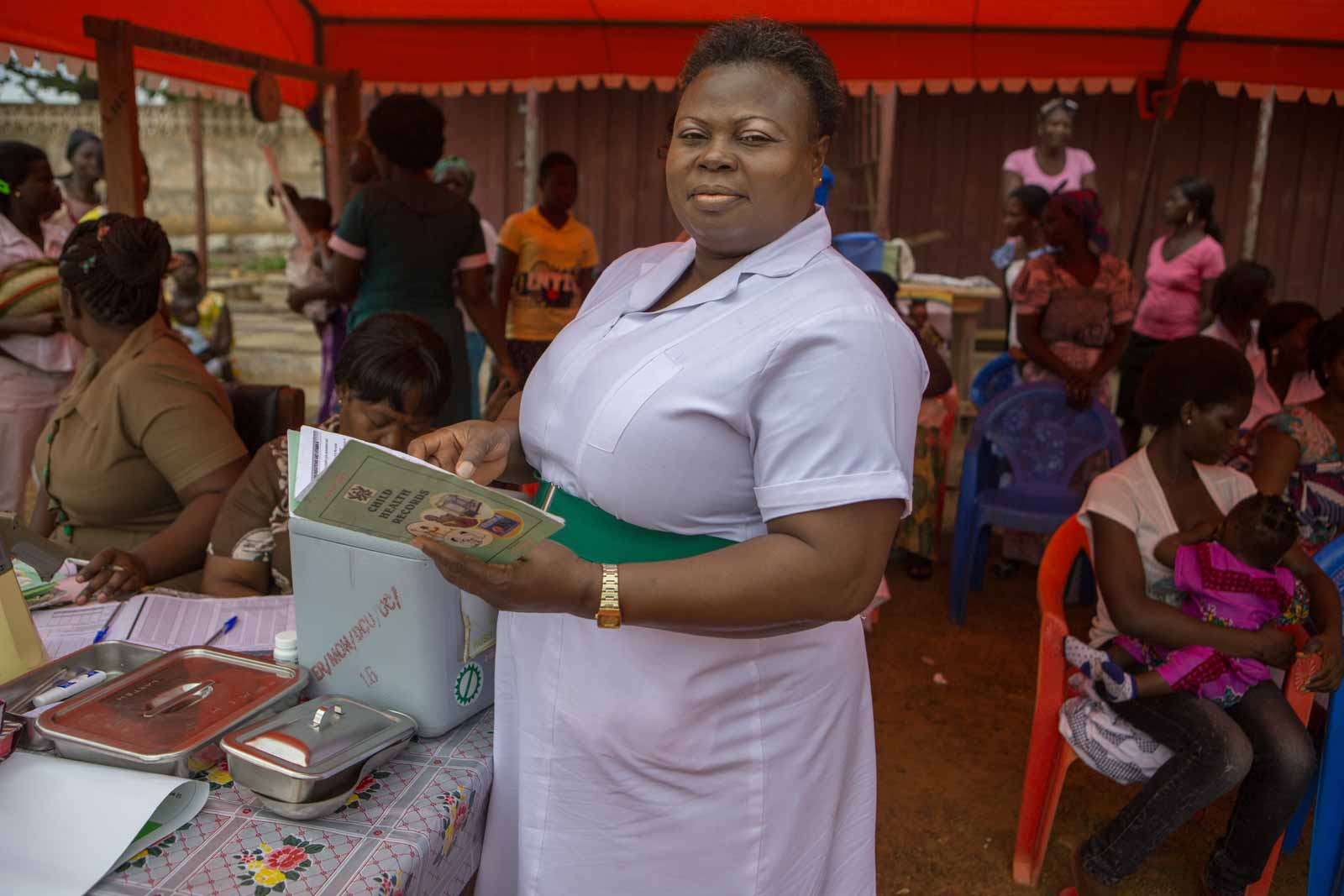 At the clinic, which is run out of an empty market stall, community health worker Mavis Adjetey weighs babies before administering vaccines.