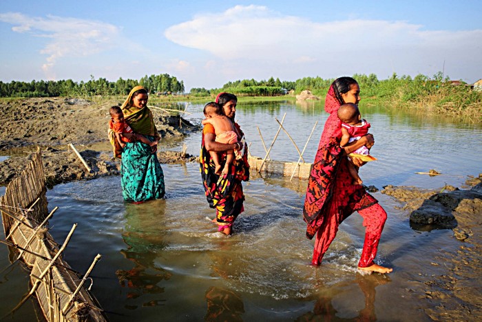 Women in Char Doglas Island, Sirajganj, Bangladesh, carry their children to get vaccinated. Most inhabitants of “chars”, the remote floodplain sediment islands that dot the Ganges delta, live a hand to mouth existence. Women often give birth at home and lack extensive formal education. However, thanks to successful vaccination campaigns these mothers are aware of the importance of immunisation and often travel long distances to get their children to the nearest vaccination center.