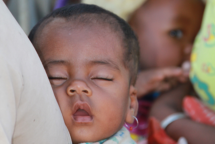 Child sleeps while strapped to its mother’s back at a health point in southern Madagascar before starting the journey home after vaccination with the pentavalent vaccine.