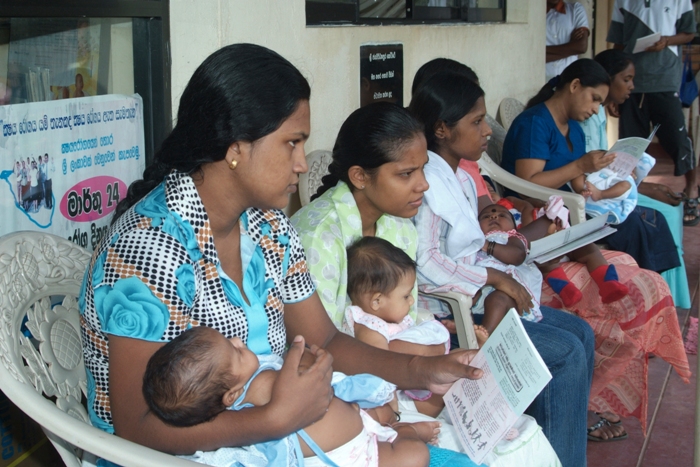 Families sit outside Pittakotte health clinic in Colombo District, waiting for their babies to be vaccinated. “Women receive a good education, so they know the value of healthy living and getting immunised,” says chief epidemiologist Nihal Abeysinghe, explaining why Sri Lanka has one of highest immunisation rates in the developing world.  