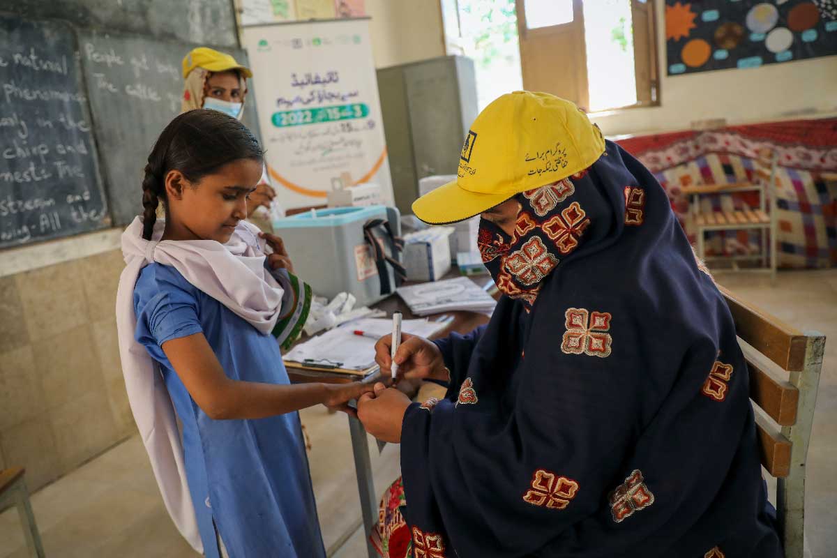A child has her fingernail coloured by a health worker denoting vaccination