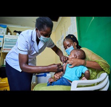 Nurse Janet Wanyama vaccinates 9-month-old Brilliant Hope against malaria while his mother Juliah Machanja watches at the Malava County Hospital Child Welfare Clinic in Kakamega, Kenya. Credit: Gavi/2021/White Rhino Films-Lameck Orina