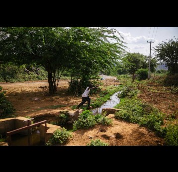 A boy leaps a rivulet in Baringo. Thorny mathenge trees dominate the landscape. Credit: Kang-Chun Cheng